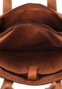 Indvendig i en brun læder tote taske med to lynlåslommer, glat tekstur og foret stofoverflade. Har en central rem til organisering.