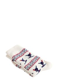 Presavijena bijela vunena čarapa s crvenim i plavim geometrijskim i životinjskim uzorcima, uključujući ptice, pleteni preko tkanine.