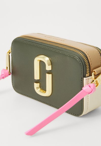 Green and beige rectangular bag with gold hardware, featuring a prominent logo and a pink strap. Textured surface with zip closure.