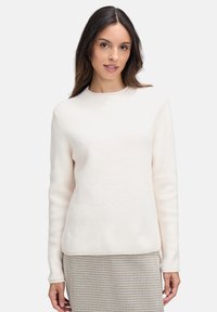 Sweter w kolorze kremowym, prążkowany, z długimi rękawami i okrągłym dekoltem, w połączeniu z spódnicą w kratę. Miękka tekstura, minimalistyczny design, dopasowany fason.