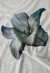 Szara koszulka z dużą, szczegółową grafiką ciemnoniebieskiego i zielonego kwiatu, z wyraźnymi płatkami i pręcikami, wykonana z miękkiego materiału.