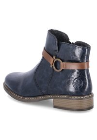 Bottine en cuir bleu marine avec une sangle marron et un accent de boucle circulaire. Finition texturée et petit talon en bois. Doublure en polaire grise.