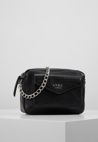 Borsa nera in finta pelle con tasca frontale a motivo coccodrillo, tracolla in catena argentata e chiusura a zip. Logo "LYDC London" presente sul fronte.