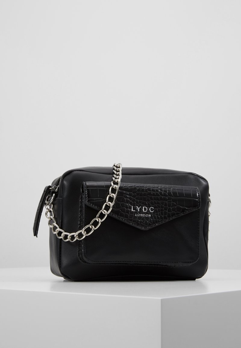 Borsa nera in finta pelle con tasca frontale a motivo coccodrillo, tracolla in catena argentata e chiusura a zip. Logo "LYDC London" presente sul fronte.