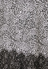 Černobílá látka se vzorem leopardího tisku, s černou krajkou s vlnkovaným okrajem na spodní straně. Celkově hladký povrch.