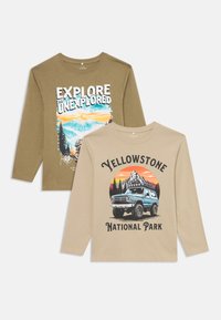 Dvoje tričiek s dlhým rukávom: olivovozelená s grafikou "Preskúmaj nepreskúmané"; béžová s textom "Národný park Yellowstone" a ilustráciou nákladného auta.