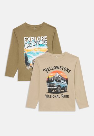 To lange langærmede t-shirts: olivengrøn med grafikken "Udforsk det Udforskede"; beige med "Yellowstone National Park" og en lastbilillustration.