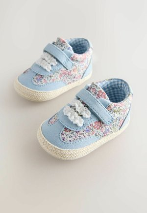 Jasnoniebieskie trampki z kwiatowymi akcentami z tkaniny, paskami na rzep oraz podeszwami o fakturze juty. Wnętrze wyściełane w kratkę.
