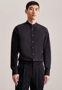 Black long-sleeve shirt with a high collar, featuring a button-front design and smooth fabric texture. Simple, modern aesthetic.