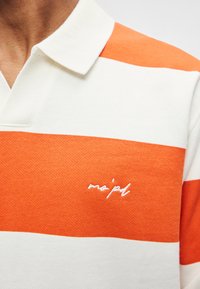 Polo com riscas alternadas em laranja e branco, fabricado em tecido texturizado, com gola e logótipo bordado na frente.