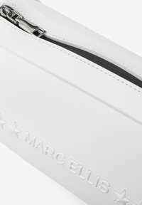 Witte etui van glad materiaal, met een zilveren rits, met het ingedrukte logo "MARC ELLIS" en twee steraccenten aan één kant.