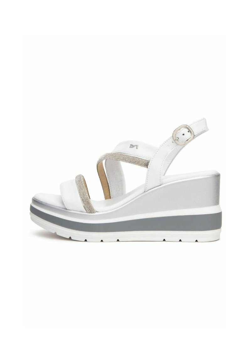 Sandalias de cuña blancas con acentos metálicos, que cuentan con correas dobles y una suela con textura. Una combinación de colores gris y blanco en la suela exterior.