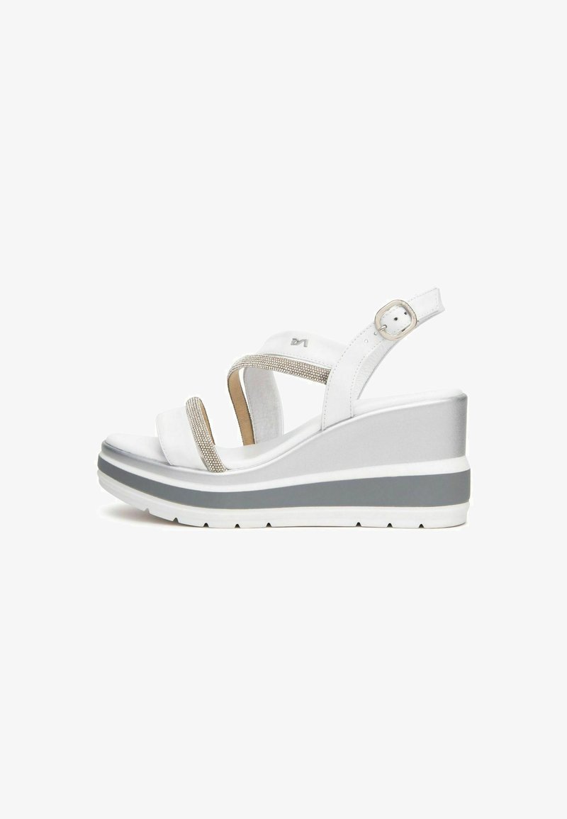 White wedge sandals with metallic accents, featuring dual straps and a textured footbed. A grey and white color scheme on the outsole.