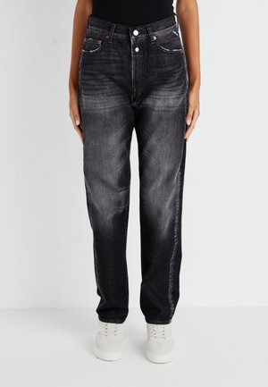 Zwarte spijkerbroek van denim met een ontspannen fit, vervaagde ontwerp, vijf zakken en contrasterende stiksels. Gepaard met witte sneakers.
