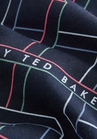 Marine stof met een ruitpatroon in wit, rood en groen lijnen, en de tekst "TED BAKER" in wit geweven, met een gestructureerd oppervlak.