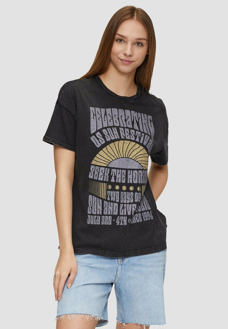 Must have must t-särk mustast puuvillast ümarate kaelustega ja lühikeste varrukatega, millel on värvikas graafiline trükis, mis tähistab päikesefestivali.