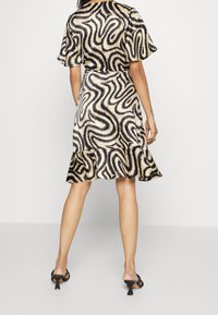 Hladké šaty ke kolenům v krémovo-černém vlnitém vzoru, s krátkými rukávy a volánkovým lemem, vyrobené z hladké tkaniny.