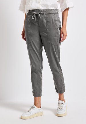 Pantalons à cordon de serrage gris en tissu doux, dotés de poches latérales, de poignets fuselés et d'une coupe décontractée. Assortis à des baskets blanches.