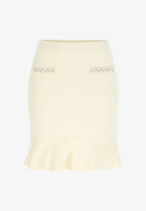 Dzianinowa spódnica w kremowym kolorze z rozkloszowanym dołem, wyposażona w dwie kieszenie ozdobione biżuterią jako dekoracyjne akcenty. Gładka faktura i dopasowany krój.