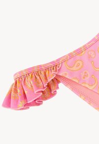 Roze stof met geel paisleypatroon, voorzien van een gerimpelde rand langs een gebogen naad.