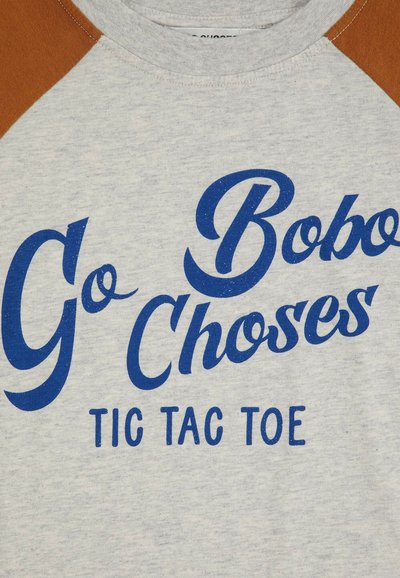 Graues T-Shirt mit kurzen Ärmeln und braunen Raglanärmeln. Die blaue Aufschrift "Go Bobo Choses TIC TAC TOE" in verspielter Schrift. Weicher Stoff.