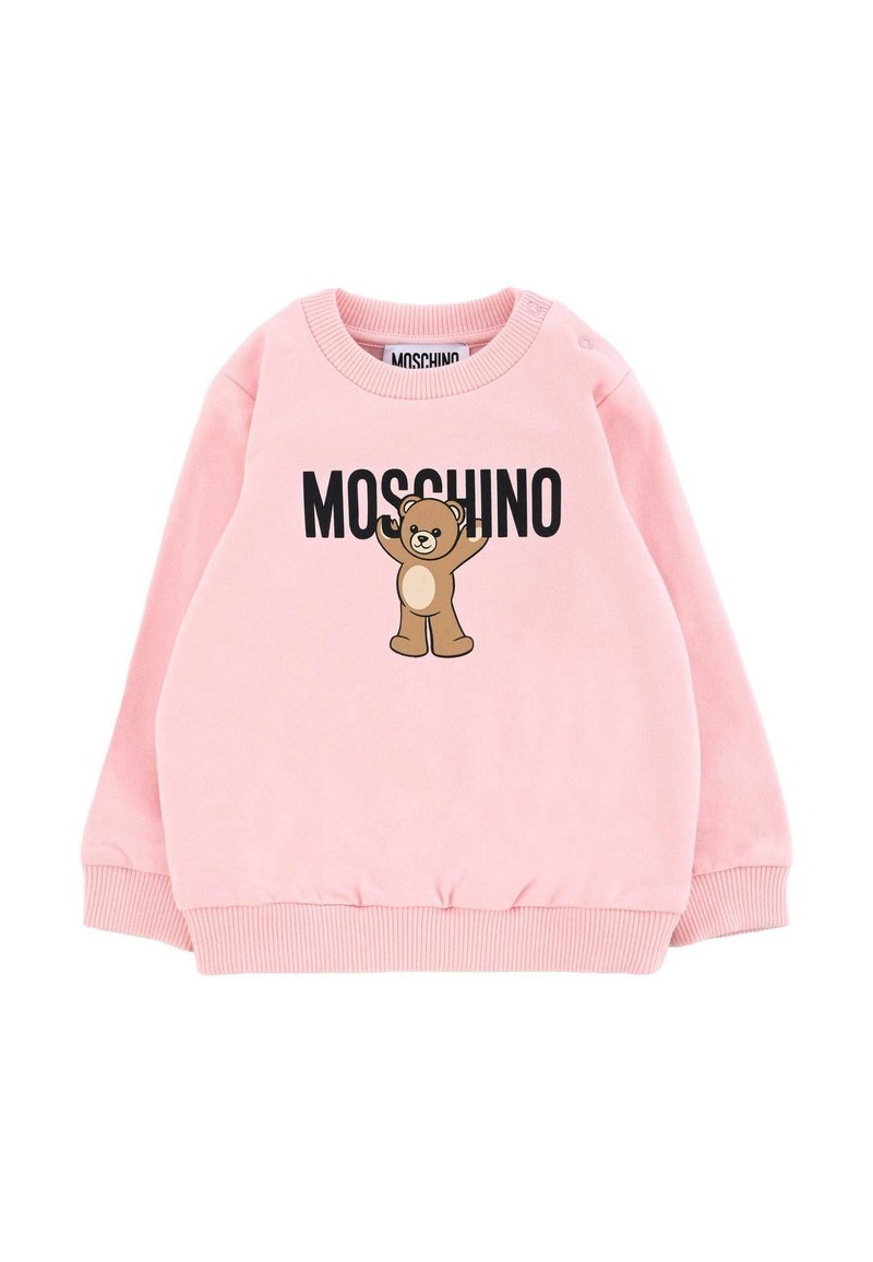 Sweatshirt en polaire rose avec des poignets et un ourlet côtelés, arborant un ours en cartoon et le texte "MOSCHINO" en noir. Fermeture à pression sur une épaule.