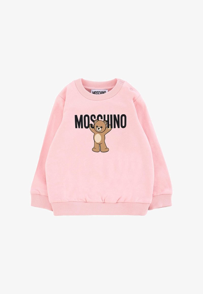 Sweatshirt en polaire rose avec des poignets et un ourlet côtelés, arborant un ours en cartoon et le texte "MOSCHINO" en noir. Fermeture à pression sur une épaule.