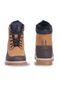 Braune Lederstiefel mit einem strukturierten dunklen Kragen, schwarzen Schnürsenkeln und einer robusten Sohle. Dicke mit einem Logo-Abzeichen und einer Schlaufe an der Rückseite.