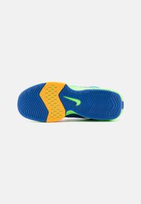 Suola della scarpa in blu, verde e arancione, con gomma testurizzata per la presa, dotata di una sezione a motivo diamante gialla e un design curvo.