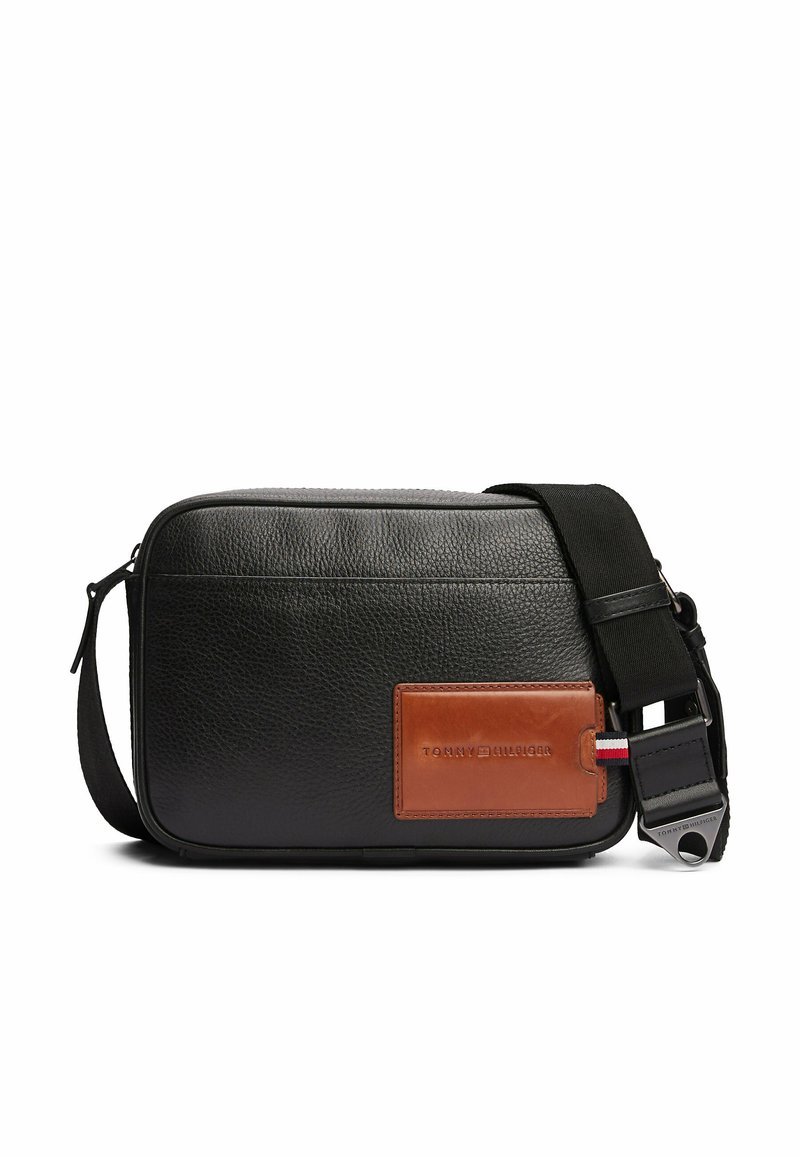 Borsa a spalla in pelle nera con superficie testurizzata, accentuata da dettagli in pelle marrone, tracolla regolabile e forma rettangolare. Presenta un patch con il logo.