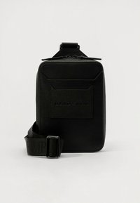 Melna pleca soma no teksturētas ādas, ar rāvējslēdzēja augšu, priekšējo logotipa uzliku un regulējamu siksnu ar reljefa detaļām.