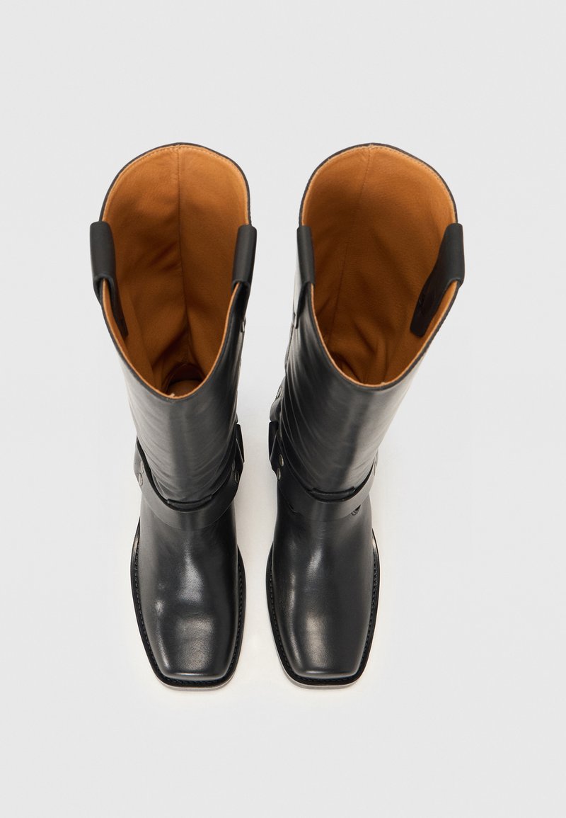 Czarne skórzane botki za kolano z kwadratowymi noskami, pomarańczową podszewką oraz bocznymi paskami z metalowymi akcentami wzdłuż cholewki.