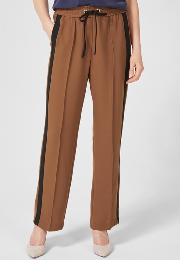 Bruna joggerbyxor med svarta sidskstripes, elastisk midjeband och dragsko. Tyget verkar slätt och lättviktigt. Lämpliga för vardagligt bruk.