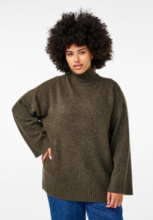 Oliveowy, oversize sweter z golfem w miękkim, teksturowanym splocie. Posiada prążkowane mankiety i dół, co zapewnia luźny krój. W połączeniu z niebieskimi dżinsami.