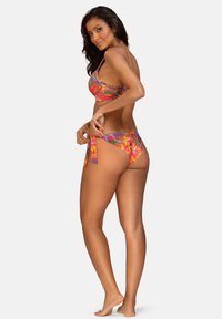 Kolorowy zestaw bikini z motywem kwiatowym; góra ma cienkie ramiączka i krótki krój, a dół wiązany jest po bokach.