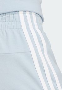 Nahaufnahme von hellblauen Sweatpants mit elastischem Bund und drei weißen vertikalen Streifen entlang der Seitennaht.