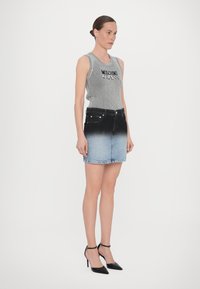 Pelēks ribots topiņš ar melnu uzrakstu "Moschino Jeans", kopā ar džinsu svārkiem, kuri izbalē no melnas uz gaiši zilu, un melniem augstpapēžu apaviem.
