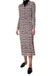 Robe à manches longues et boutonnée avec un motif en ondulations dans des couleurs blanc, noir et rouille. Des chaussures plates avec des accents dorés complètent le look.