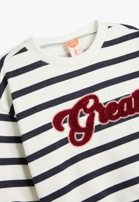 Maglione a maniche lunghe a righe in bianco e blu navy, con un morbido ricamo rosso "Great". Tessuto di cotone soffice con colletto a coste.