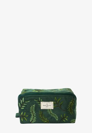 Grüne rechteckige Tasche mit Reißverschluss, bestickt mit Farnmustern und einem weißen Etikett mit der Aufschrift The Flat Lay Co. London vorne.