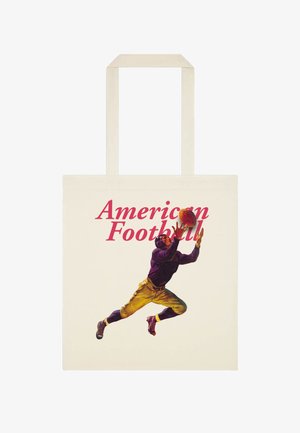 Handtaske med illustration af en fodboldspiller i vintage uniform, der springer for at fange en bold, tekst "American Football" over spilleren.