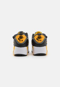 Črne in rumene Nike Air superge z teksturiranim zadnjim delom, belimi podplati in izrazitim logotipom. Imajo oblazinjen ovratnik in mrežasto zgornji del.