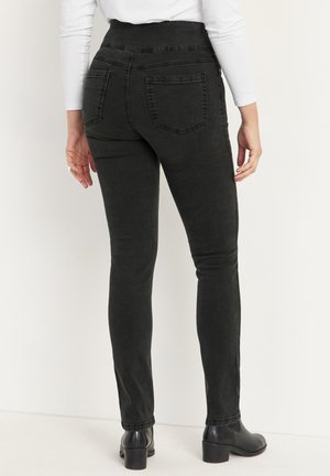 Svarta denimjeans med hög midja, smal passform och bakfickor, med en slät yta och minimal sömdetalj. Bärs med svarta stövlar.