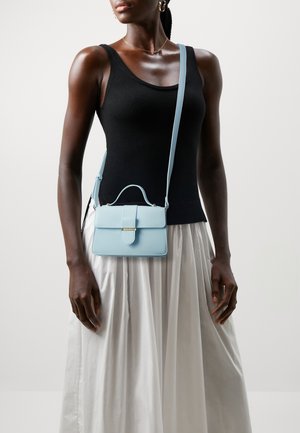 Lyseblå læderhåndtaske med struktureret form, topgreb og aftagelig skulderrem. Har en frontklap og hardware i guldfarve.