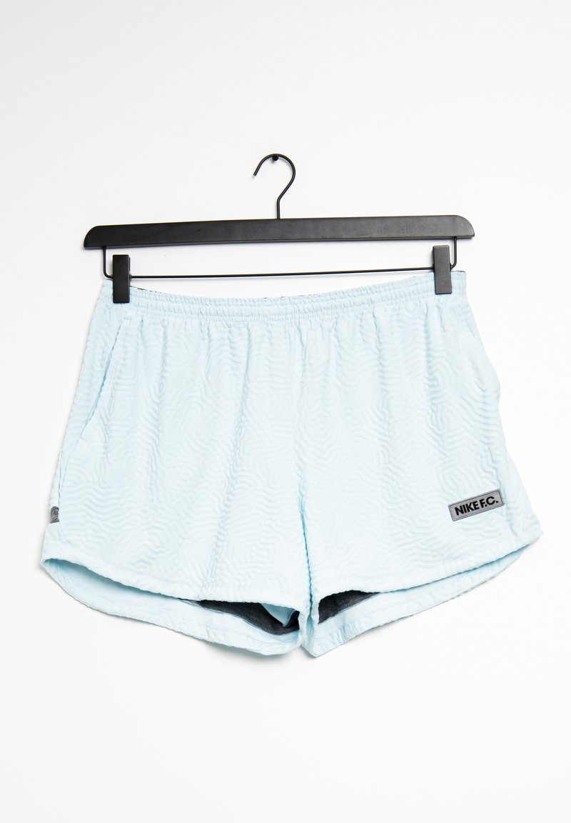 Shorts de sport Nike F.C. bleu clair avec un motif texturé en vagues, taille élastique et poches latérales. Doublure intérieure noire, étiquette visible.