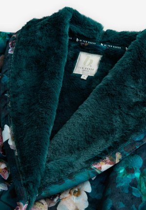 Syvä turkoosi tekoturkiskasari kukkakuosisessa takissa, jossa on Ted Baker London -label ja koko pieni -tagi.