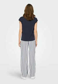 Haut à manches courtes bleu marine associé à un pantalon large à rayures verticales blanches et bleues. Tissu doux avec une coupe décontractée, design minimaliste.