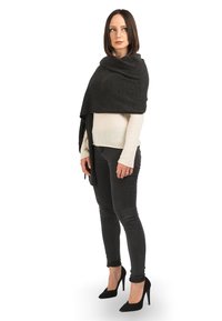 Mørkegrå sjal hænger over en lys sweater med en blød tekstur. Figuren har sorte jeans og høje hæle på og står mod en hvid baggrund.