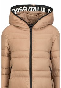 Helle beige Steppjacke mit Reißverschluss, Kapuze und schwarzen Akzenten. Verfügt über ein horizontal gestepptes Design und seitliche Taschen. Text auf der inneren Kapuze.