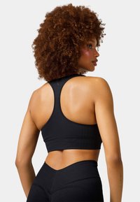 Black athletic crop top with racerback design, ribbed texture, and a fitted silhouette. Contrasting details along the seams and edges.